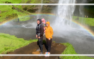 Iceland family vacation in front of waterfall and rainbow.