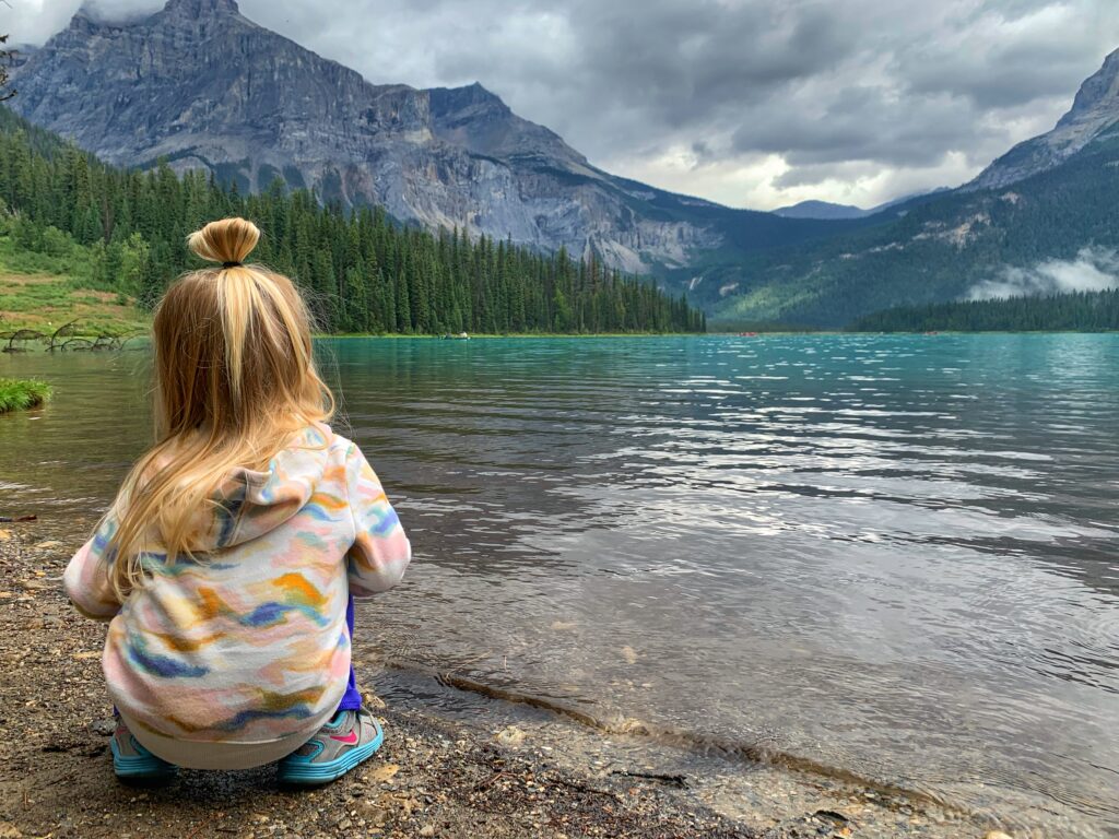 toddler sitting in front of emerald lake yoho national park